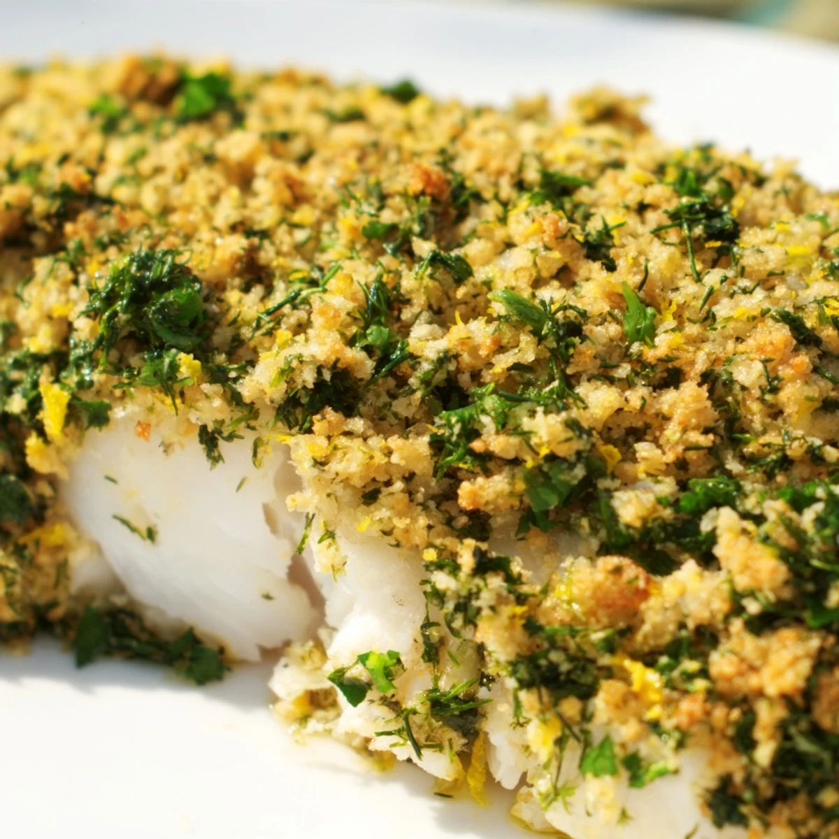 A close look at tender baked hake with crispy lemon herb topping, garnished with fresh parsley.